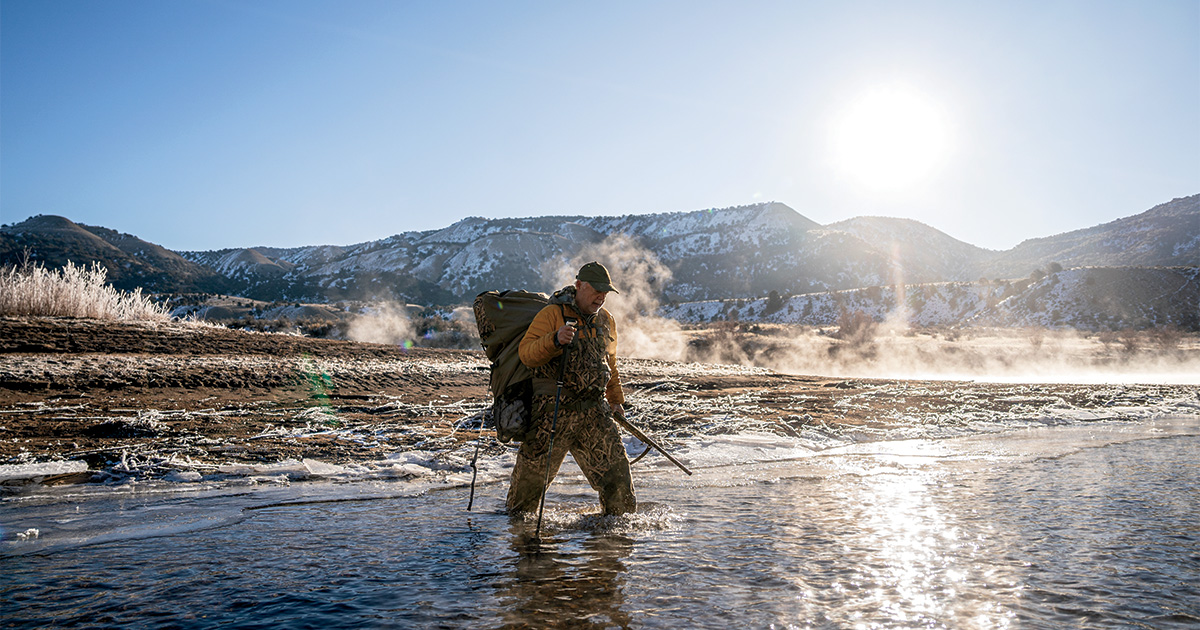 Hunter wading through river. Photo by Greg Sweeney